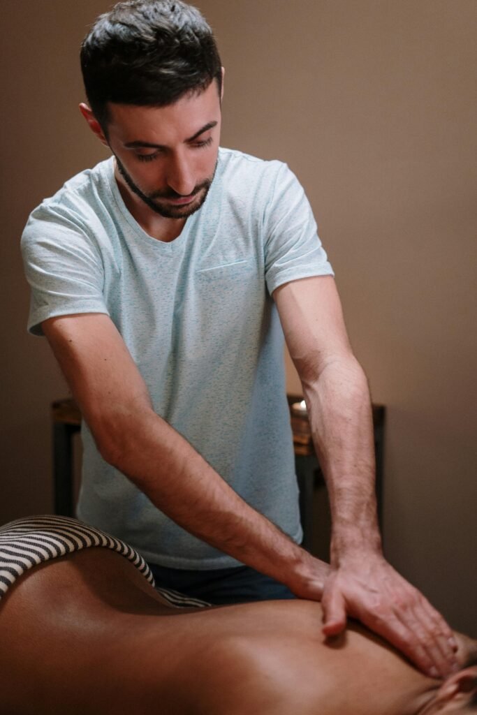 A male therapist providing a relaxing massage in a cozy spa setting.